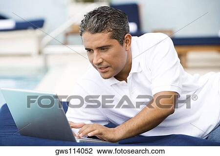 Close-up of a mid adult man using a laptop View Large Photo Image Stock Image - Close-up of a mid adult man using a laptop. Fotosearch