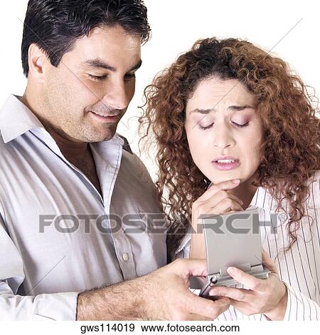 Stock Photo - Close-up of a young woman and a mid adult man using a calculator. Fotosearch