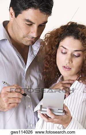 Close-up of a young woman and a mid adult man using a calculator View Large Photo Image Stock Photograph - Close-up of a young woman and a mid adult man using a calculator. Fotosearch