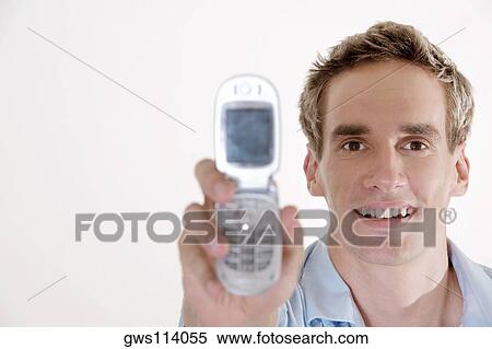 Portrait of a young man holding a mobile phone View Large Photo Image Stock Photography - Portrait of a young man holding a mobile phone. Fotosearch