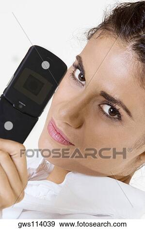 Portrait of a young woman holding a mobile phone View Large Photo Image Stock Photo - Portrait of a young woman holding a mobile phone. Fotosearch