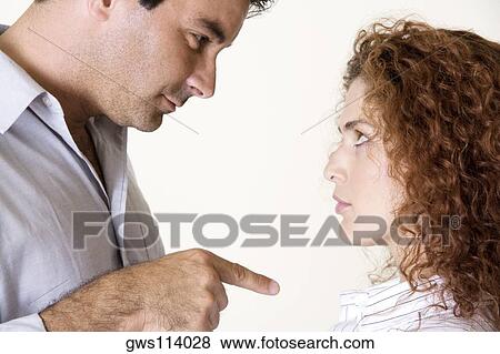 Side profile of a mid adult man pointing to a young woman View Large Photo Image Stock Photo - Side profile of a mid adult man pointing to a young woman. Fotosearch
