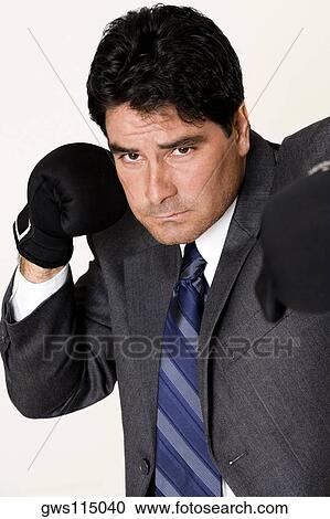 Stock Image - Portrait of a businessman wearing boxing gloves. Fotosearch