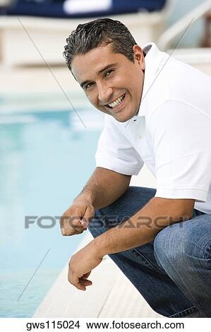 Portrait of a mid adult man crouching at the poolside View Large Photo Image Picture - Portrait of a mid adult man crouching at the poolside. Fotosearch