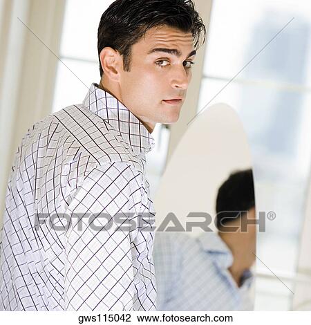 Stock Image - Portrait of a young man in front of a mirror. Fotosearch