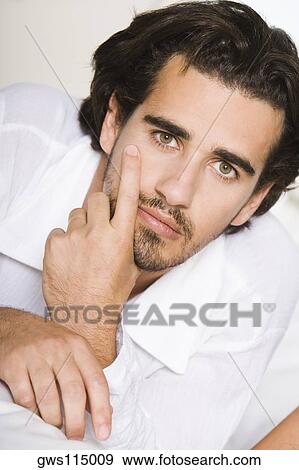 Stock Photo - Portrait of a young man lying on a bed. Fotosearch