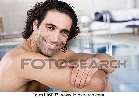 Stock Photo - Close-up of a mid adult man sitting at the poolside. Fotosearch