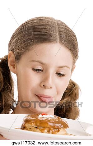 Close-up of a girl holding a donut in a plate licking her lips View Large Photo Image Stock Image - Close-up of a girl holding a donut in a plate licking her lips. Fotosearch