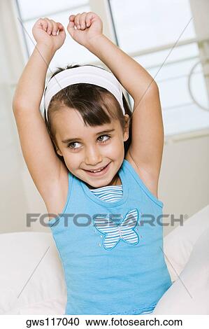 Stock Image - Close-up of a girl smiling with her arms raised. Fotosearch