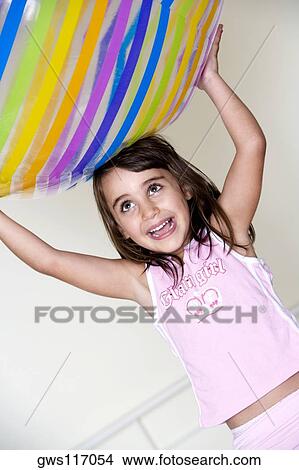 Girl carrying an inflatable ball over her head View Large Photo Image Picture - Girl carrying an inflatable ball over her head. Fotosearch