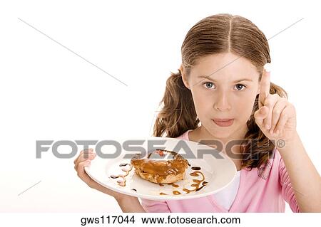 Portrait of a girl holding a donut in a plate with cream on the tip of her finger View Large Photo Image Picture - Portrait of a girl holding a donut in a plate with cream on the tip of her finger. Fotosearch