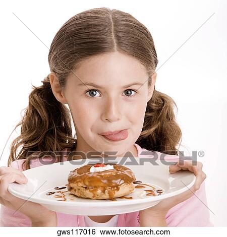 Portrait of a girl holding a donut in a plate licking her lips View Large Photo Image Stock Photograph - Portrait of a girl holding a donut in a plate licking her lips. Fotosearch