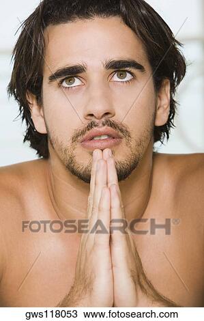 Close-up of a young man praying View Large Photo Image Stock Image - Close-up of a young man praying. Fotosearch