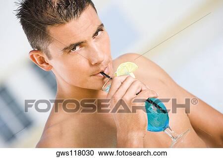 Stock Image - Portrait of a young man drinking a cocktail. Fotosearch