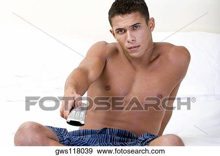Portrait of a young man holding a remote control View Large Photo Image Stock Photo - Portrait of a young man holding a remote control. Fotosearch
