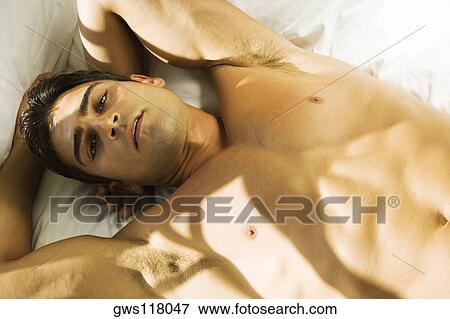 Stock Photo - Portrait of a young man lying on his back looking serious. Fotosearch
