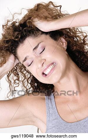 Close-up of a young woman with her hands in her hair View Large Photo Image Stock Photo - Close-up of a young woman with her hands in her hair. Fotosearch