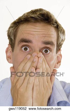 Portrait of a young man covering his mouth with his hands View Large Photo Image Stock Image - Portrait of a young man covering his mouth with his hands. Fotosearch