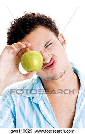 Portrait of a young man holding an apple View Large Photo Image Stock Photo - Portrait of a young man holding an apple. Fotosearch