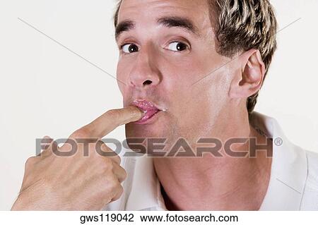 Stock Image - Portrait of a young man licking his finger. Fotosearch