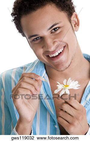Portrait of a young man plucking petals of a flower View Large Photo Image Stock Image - Portrait of a young man plucking petals of a flower. Fotosearch