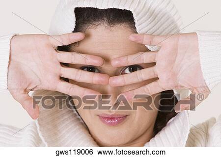 Portrait of a young woman looking through her fingers View Large Photo Image Stock Photograph - Portrait of a young woman looking through her fingers. Fotosearch