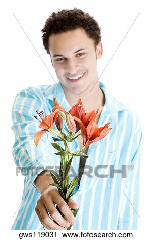 Young man holding flowers and smiling View Large Photo Image Stock Image - Young man holding flowers and smiling. Fotosearch