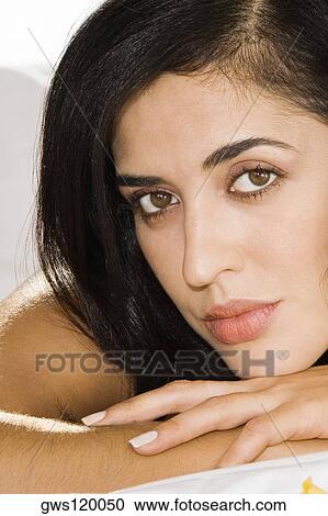 Stock Image - Portrait of a mid adult woman lying on the bed. Fotosearch
