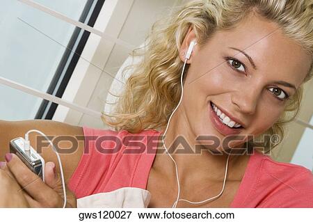Portrait of a young woman listening to an MP3 player View Large Photo Image Stock Photo - Portrait of a young woman listening to an MP3 player. Fotosearch