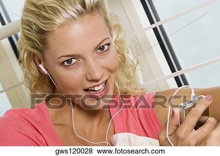 Stock Photo - Portrait of a young woman listening to an MP3 player. Fotosearch