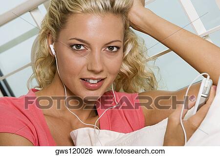 Stock Photograph - Portrait of a young woman listening to an MP3 player. Fotosearch