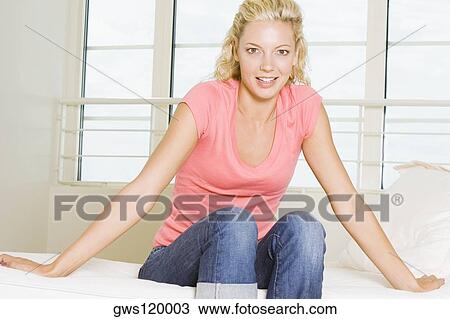 Portrait of a young woman sitting on a couch View Large Photo Image Stock Image - Portrait of a young woman sitting on a couch. Fotosearch