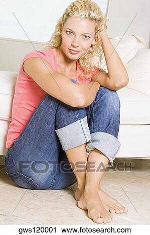 Stock Image - Portrait of a young woman sitting on the floor. Fotosearch