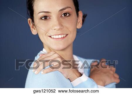 Stock Image - Side profile of a young woman with her arms crossed. Fotosearch