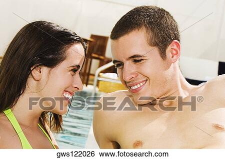 Close-up of a young couple smiling at the poolside View Large Photo Image Stock Photograph - Close-up of a young couple smiling at the poolside. Fotosearch