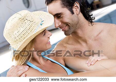 Stock Image - Close-up of a young woman and a mid adult man looking at each other. Fotosearch