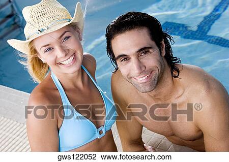 Portrait of a young woman and a mid adult man smiling at the poolside View Large Photo Image Stock Image - Portrait of a young woman and a mid adult man smiling at the poolside. Fotosearch