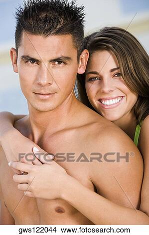 Portrait of a young woman embracing a young man from behind View Large Photo Image Picture - Portrait of a young woman embracing a young man from behind. Fotosearch
