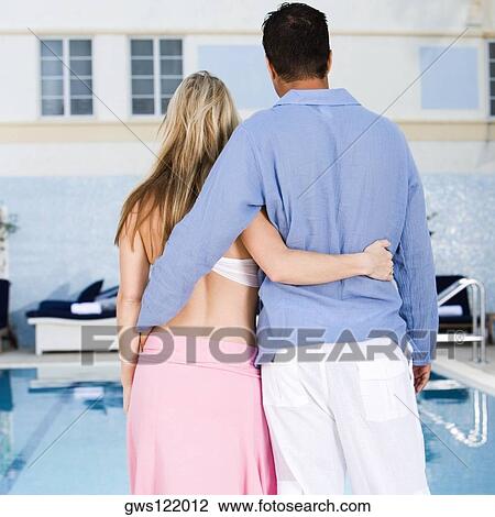 Rear view of a young woman and a mid adult man standing at the poolside View Large Photo Image Stock Image - Rear view of a young woman and a mid adult man standing at the poolside. Fotosearch