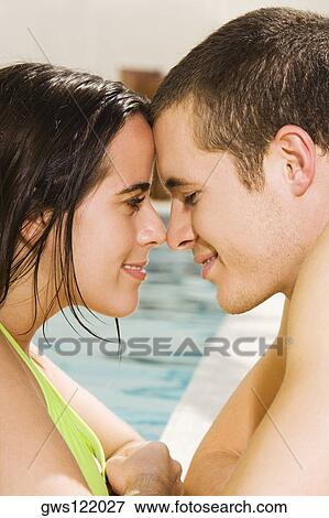 Stock Photo - Side profile of a young couple at the poolside. Fotosearch