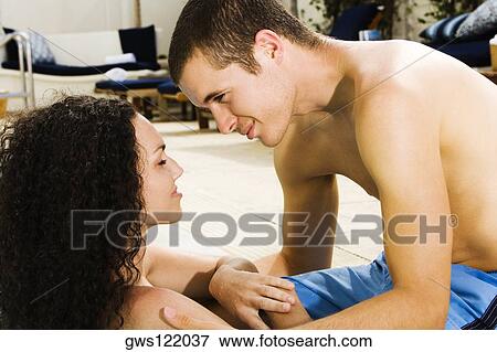 Stock Photo - Side profile of a young couple at the poolside. Fotosearch
