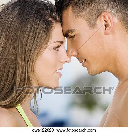 Stock Photo - Side profile of a young couple rubbing their noses. Fotosearch