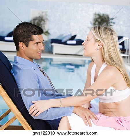 Young woman and a mid adult man sitting at the poolside View Large Photo Image Stock Image - Young woman and a mid adult man sitting at the poolside. Fotosearch