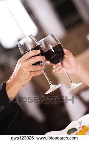 Stock Photograph - Close-up of a man and a woman toasting glasses of red wine. Fotosearch