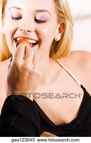 Stock Image - Close-up of a man feeding a strawberry to a young woman. Fotosearch