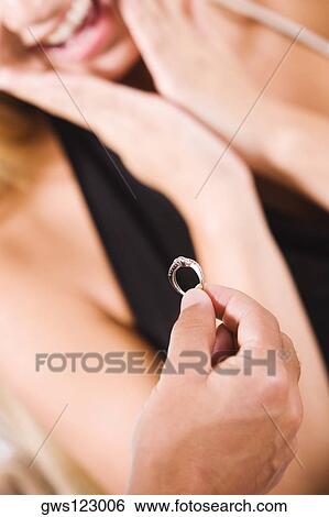Close-up of a man giving an engagement ring to a young woman View Large Photo Image Stock Photograph - Close-up of a man giving an engagement ring to a young woman. Fotosearch