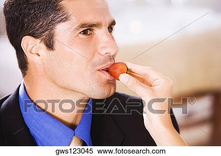Close-up of a woman feeding a businessman a strawberry View Large Photo Image Stock Photography - Close-up of a woman feeding a businessman a strawberry. Fotosearch