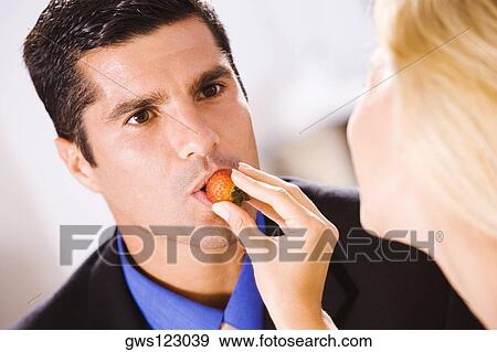 Close-up of a young woman feeding a mid adult man a strawberry View Large Photo Image Stock Photo - Close-up of a young woman feeding a mid adult man a strawberry. Fotosearch