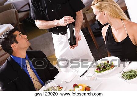 Mid adult man and a young woman sitting at a table with a waiter standing beside them View Large Photo Image Stock Image - Mid adult man and a young woman sitting at a table with a waiter standing beside them. Fotosearch