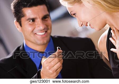 Mid adult man giving an engagement ring to a young woman View Large Photo Image Stock Image - Mid adult man giving an engagement ring to a young woman. Fotosearch